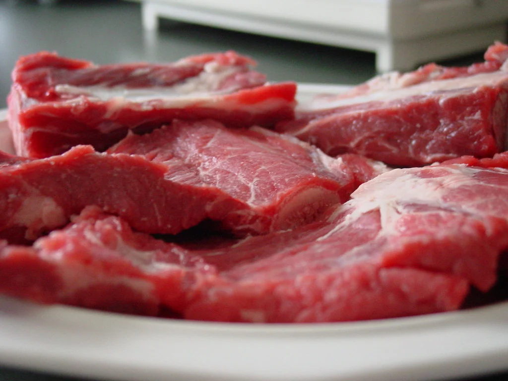 Raw bone-in beef short ribs arranged on a plate